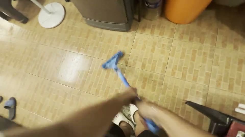 First-person video still of someone mopping a home floor