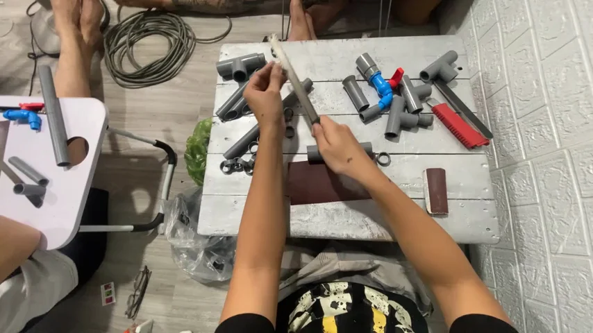 First-person video still of hands assembling small parts on a worktable